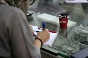 mujer cuaderno escribiendo con un baso rojo